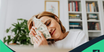 Mujer feliz con dinero en la mano que representa la Independencia Financiera